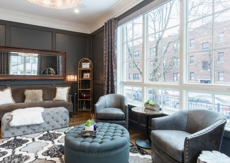 A well-decorated living room with charcoal grey walls and a bright window