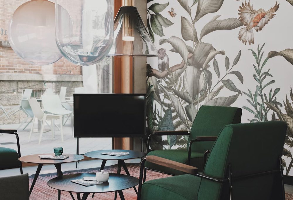 A beautiful living room with nature-themed wallpaper on the one wall and a large floor-to-ceiling window on the other